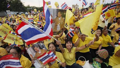 	Đám đông người dân Thái quỳ rạp và vẫy cờ, giơ cao ảnh chân dung của nhà vua Thái Lan để đón chào xe của Ngài đi qua.