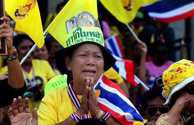  	Một người phụ nữ Thái Lan khóc khi xe của nhà vua Thái Lan và đoàn tuỳ tùng đi qua.