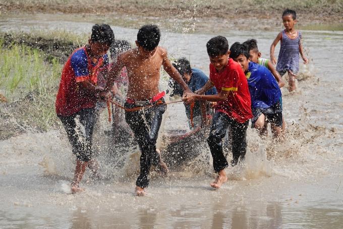 Một nhóm thanh niên, trẻ em cùng tham gia cày để chuẩn bị cấy mạ.